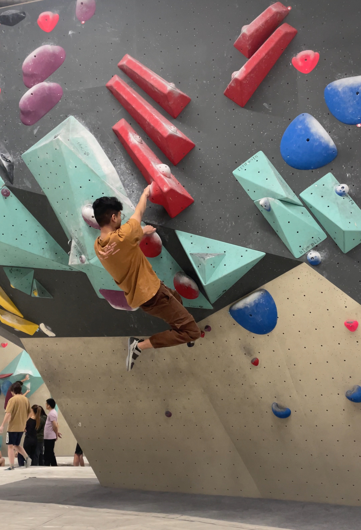 Naman mid-move on an overhang at a Sydney bouldering gym
