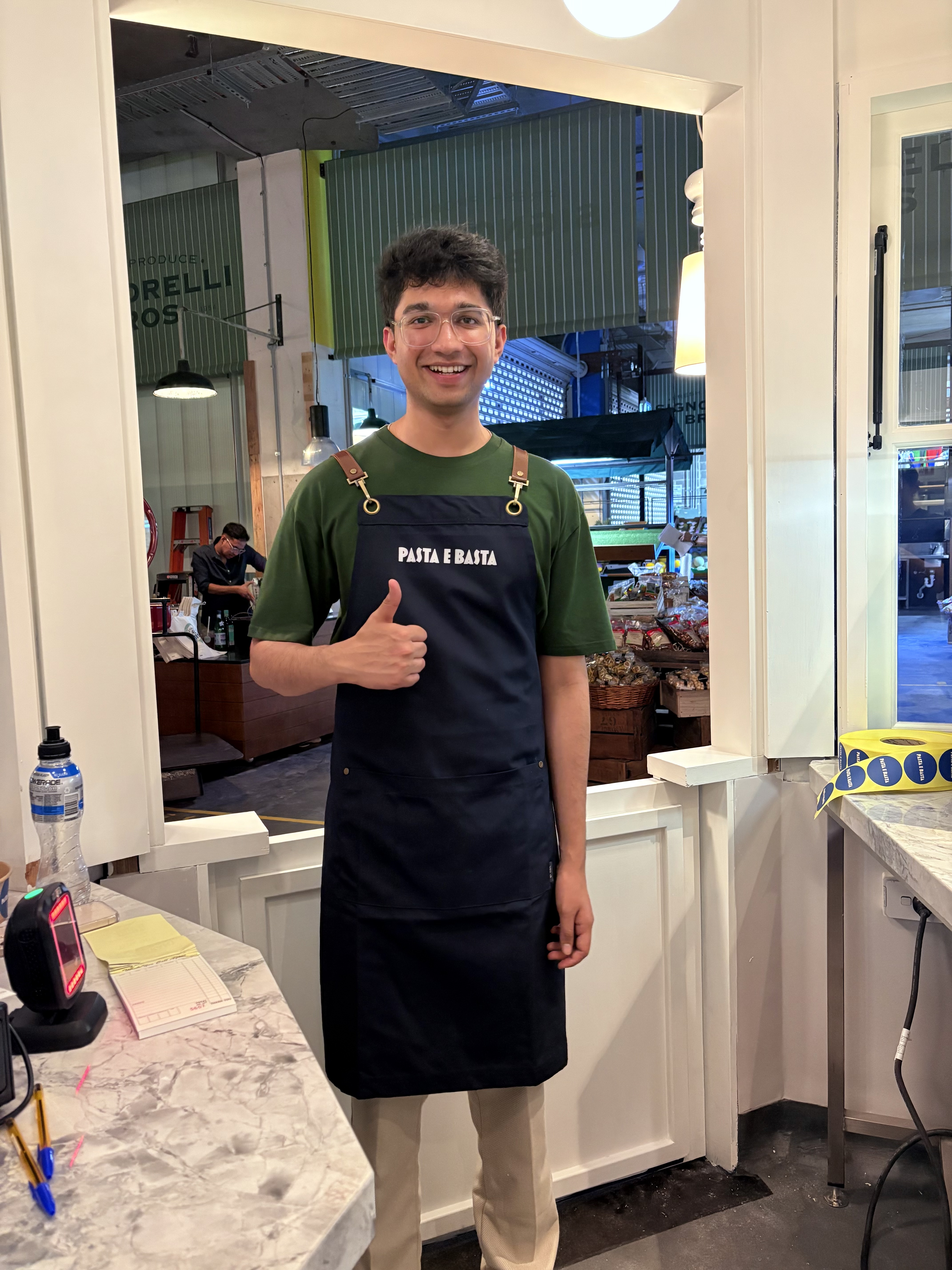 Naman in a Pasta e Basta apron behind the counter at a Sydney food market